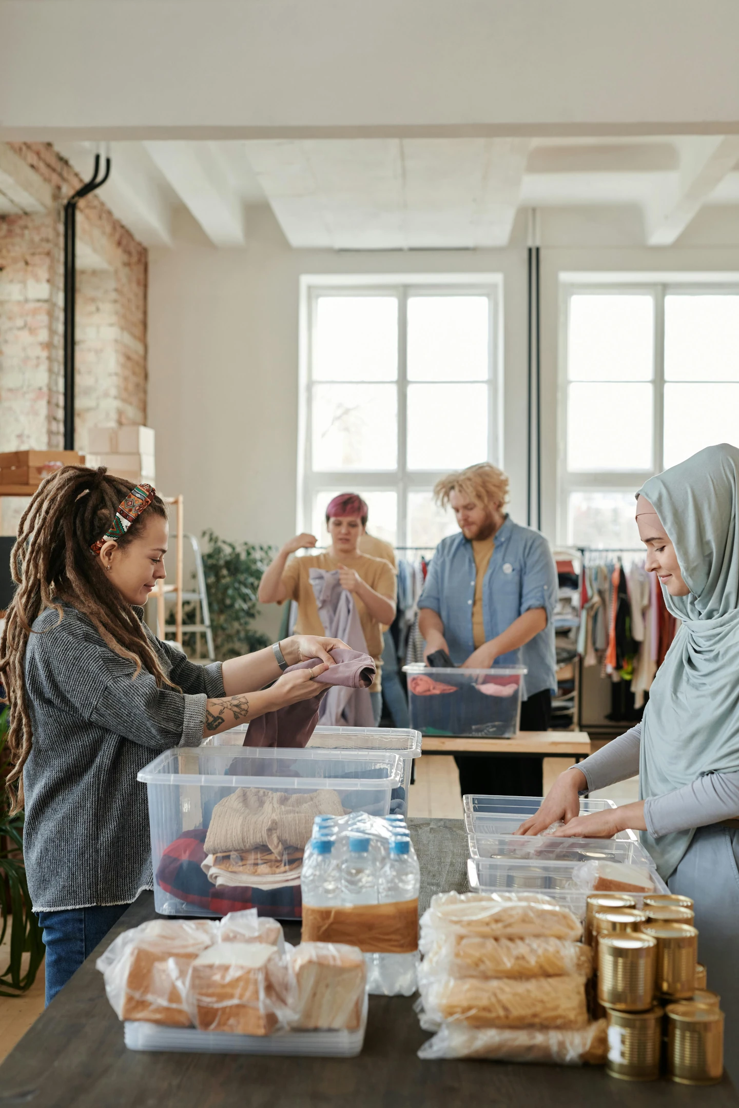 Diverse volunteers sorting clothes and food donations in a warehouse.